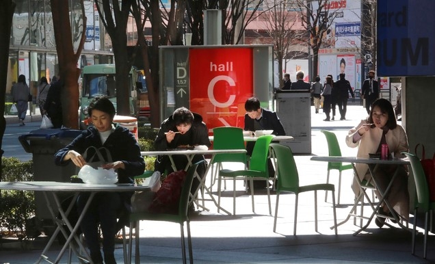 일본 수도 도쿄 시내에 있는 편의점 앞에서 16일 직장인들이 코로나19 방역 지침에 따라 거리를 두고 앉은 채 각자 도시락으로 점심식사를 하고 있다.