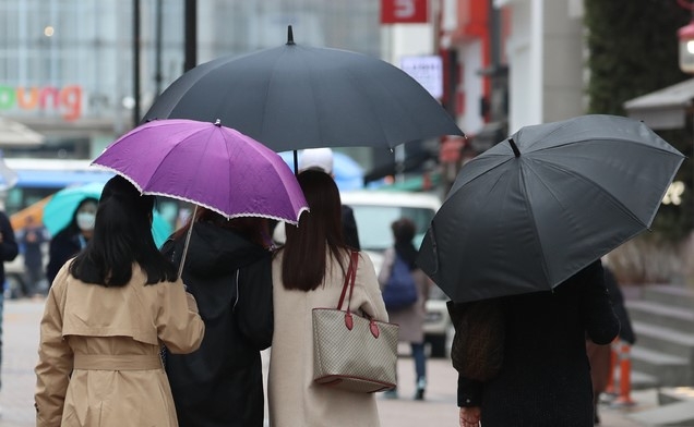 전국에 봄비가 내리기 시작한 12일 서울 명동 거리에서 시민이 우산을 쓰고 있다.
