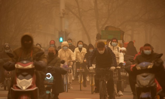 15일 중국 베이징이 공기 오염과 황사로 온통 뿌연 가운데 마스크를 쓴 출근길 시민들이 교차로를 지나고 있다. 중국 기상대는 베이징과 북부에서 발생한 심각한 황사로 올해 첫 황사 경보를 발령했다.