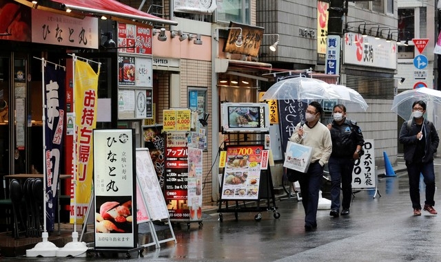 8일 일본 도쿄에서 코로나19 확산 방지를 위해 마스크를 쓴 시민들이 술집과 식당이 즐비한, 거의 텅 빈 거리를 걷고 있다.