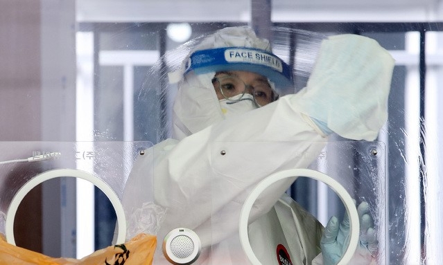 코로나19 신규 확진자가 7일 만에 300명대로 감소한 15일 오후 서울 용산구 서울역 앞에 마련된 임시선별검사소에서 의료진이 소독을 하고 있다.