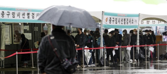 코로나19 신규 확진자가 452명으로 집계된 20일 서울역 광장에 마련된 중구 임시 선별검사소에서 시민들이 우산을 쓰고 검사를 받기 위해 줄지어 기다리고 있다.