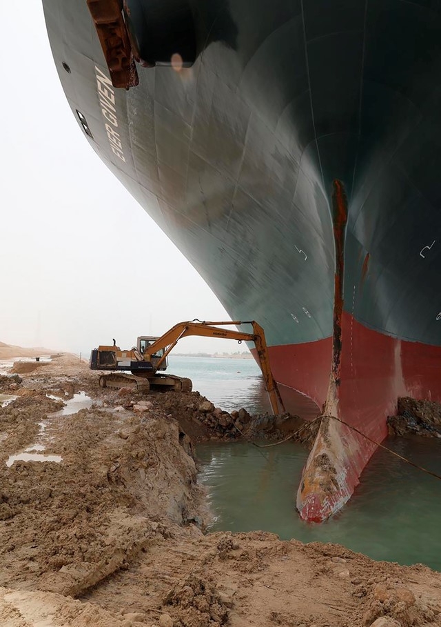 이집트 수에즈 운하를 가로막고 선 에버기븐호 앞의 굴착기. 25일(현지시간) 수에즈운하관리청(SCA)이 제공한 사진.