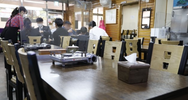 중앙재난안전대책본부가 현행중인 사회적 거리두기 수도권 2단계, 비수도권 1.5단계를 다음달 2일 자정까지 3주 더 연장한다고 발표한 지난 9일 서울 서초구의 한 식당에서 가림막을 사이에 둔 직장인들이 점심식사를 하고 있다.