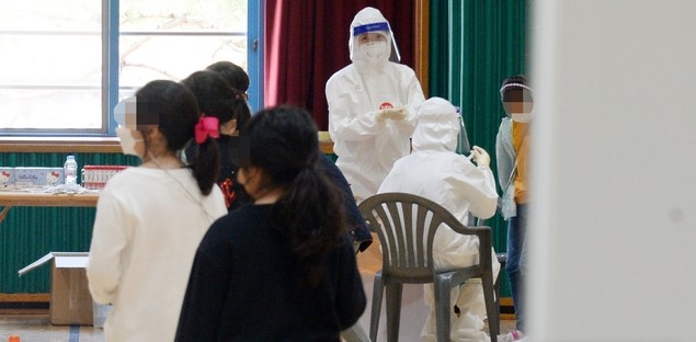 전북 전주시 덕진구 호성동에 위치한 전주만수초등학교에서 코로나19 확진자가 발생한 7일 의료진들이 학교 강당에 이동 선별진료소를 설치하고 학생들의 검체를 채취하고 있다.
