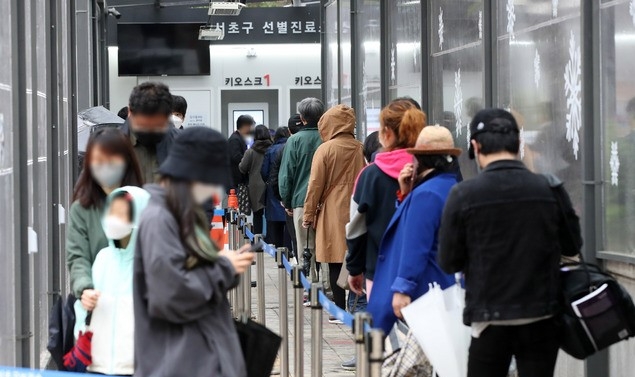 코로나19 신규 확진자가 587명으로 집계된 12일 오후 서울 서초구 서초보건소에 마련된 코로나19 선별진료소에서 시민들이 검사를 받기 위해 줄 서 있다.