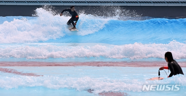 낮 기온이 28도까지 오르는 등 초여름 날씨를 보인 21일 오후 경기도 시흥시 인공 서핑시설 '웨이브 파크'에서 서퍼들이 파도를 타고 있다.