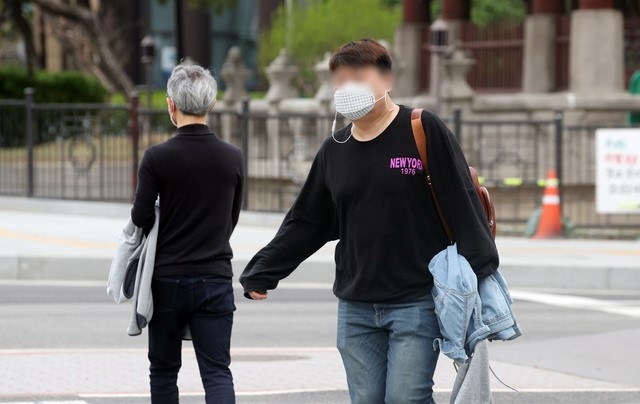 낮 기온이 최고 28도까지 오르는 등 초여름 날씨가 예보된 22일 오전 서울 종로구 광화문네거리에서 출근길 시민이 겉옷을 벗어 들고 있다.