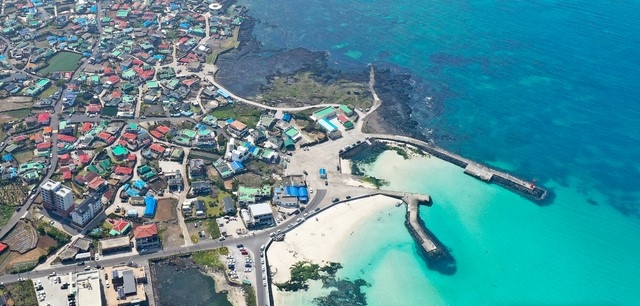 비교적 맑은 날씨를 보인 29일 오후 제주시 구좌읍 김녕해수욕장 인근 상공에서 바라본 푸른 바다가 내륙에 위치한 주택의 다채로운 지붕색과 대조를 이루며 시선을 사로 잡고 있다.