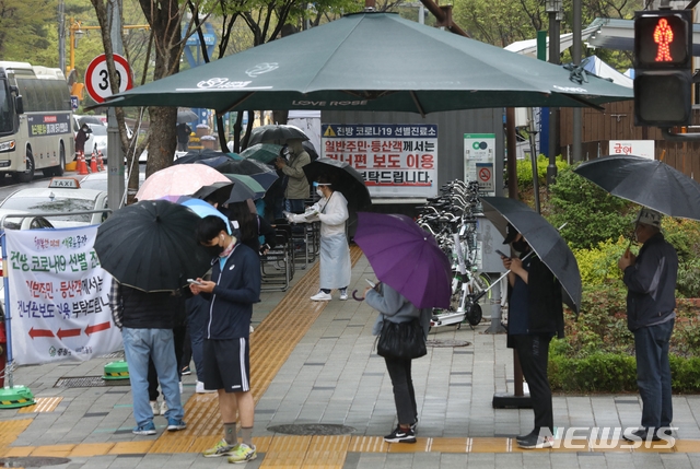 지난 12일 서울 중랑구 보건소에 마련된 코로나19 선별진료소에서 시민들이 우산을 쓰고 대기하고 있다.