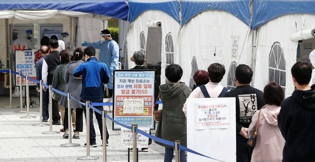 코로나19 신규 확진자가 775명으로 집계된 28일 서울 송파구 올림픽공원 앞에 마련된 임시선별진료소에서 시민들이 검사를 받기 위해 길게 줄지어 기다리고 있다.