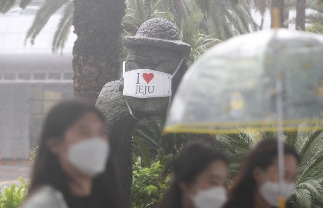 제주국제공항에서 관광객들이 비를 피해 렌터카 보관소로 이동하고 있다.