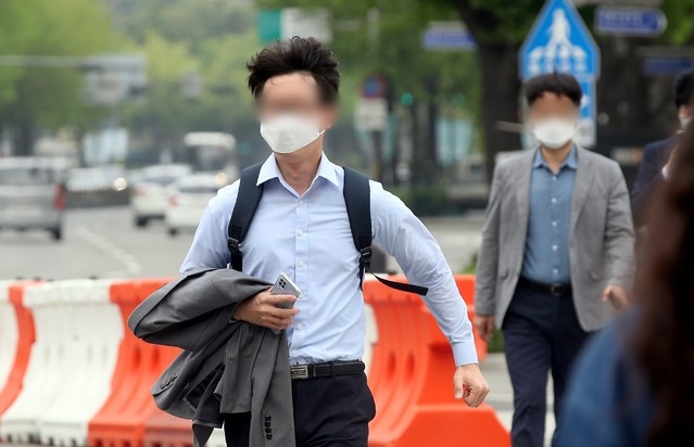 지난달 22일 오전 서울 종로구 광화문네거리에서 한 시민이 겉옷을 벗어 들고 있다. 
