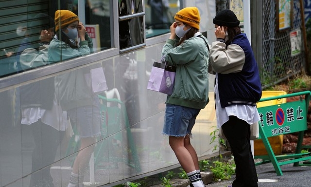 일본의 황금연휴 '골든위크'가 시작되는 29일 도쿄 시부야 구역에서 코로나19 확산을 막기 위해 마스크를 쓴 여성들이 거리의 유리를 들여다보며 옷매무새를 고치고 있다. 일본이 히로히토 일왕의 생일인 4월29일부터 5월5일 어린이날까지 '골든위크'로 불리는 연휴를 맞은 가운데 수도권 4개 광역지방자치단체장은 '골든위크' 연휴를 집에서 보낼 것을 호소했다.