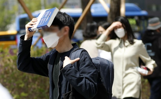 서울 낮 최고 기온이 28도로 무더운 날씨를 보인 지난달 21일 서울 중구 청계광장 인근에서 시민들이 책과 손으로 햇빛을 가리고 있다.