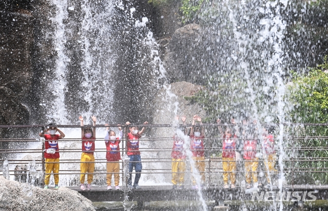 초여름 날씨를 보인 12일 오후 경기도 안산시 노적봉인공폭포공원을 찾은 어린이들이 시원하게 쏟아지는 폭포수를 바라보며 즐거워하고 있다.