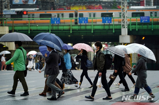 13일 일본 도쿄에서 코로나19 확산을 막기 위해 마스크를 쓴 시민들이 우산을 쓰고 건널목을 건너고 있다.
