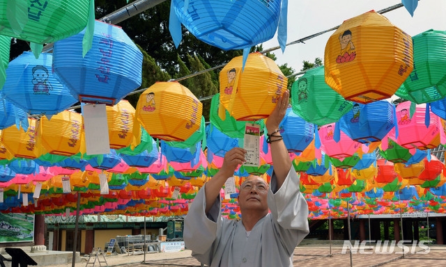 불기 2565(2021)년 부처님 오신 날을 앞두고 6일 오후 경북 영천시 청통면 은해사 극락보전 앞에서 한 스님이 형형색색 연등을 경내에 매달고 있다.