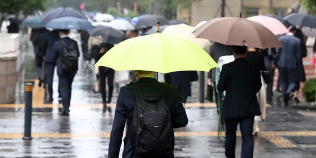 이슬비가 내리고 있는 17일 오전 서울 영등포구 여의도역 인근에서 시민들이 우산을 쓰고 걸어가고 있다.