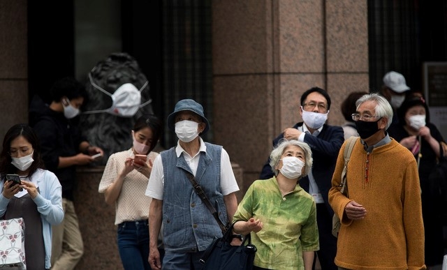 21일 일본 도쿄의 유명 긴자 쇼핑가 교차로에서 시민들이 코로나19 확산 방지를 위해 마스크를 쓰고 건너가고 있다. 일본 정부는 21일 미국 모더나 백신과 다국적 제약사 아스트라제네카 백신의 사용을 정식 승인했다.