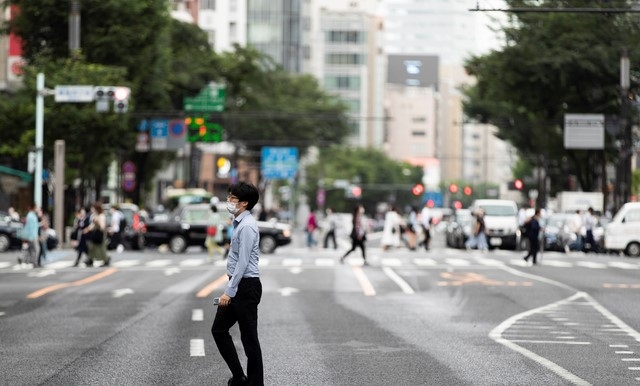 21일 일본 도쿄의 긴자 쇼핑가에서 코로나19 확산 방지를 위해 마스크를 쓴 한 남성이 길을 건너고 있다.