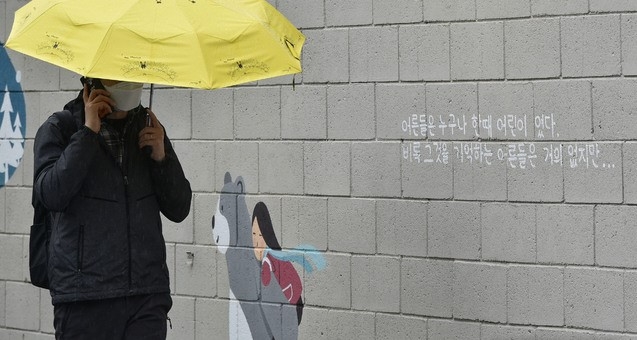 봄비가 내린 12일 오후 대구 중구 삼덕동 벽화 길에서 한 시민이 우산을 쓴 채 걸어가고 있다. 최근 경북 구미에서 3세 여아가 홀로 방치된 채 사망하는 등 아동학대 사건이 끊이지 않는 가운데 벽화에 적힌 문구가 시선을 사로잡는다.