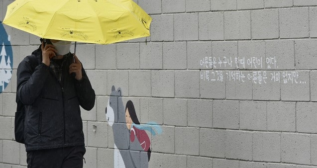 봄비가 내린 지난 4월 12일 오후 대구 중구 삼덕동 벽화 길에서 한 시민이 우산을 쓴 채 걸어가고 있다. 최근 경북 구미에서 3세 여아가 홀로 방치된 채 사망하는 등 아동학대 사건이 끊이지 않는 가운데 벽화에 적힌 문구가 시선을 사로잡는다.