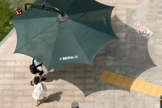 서울 낮 기온이 30도까지 오르며 초여름 날씨를 보인 지난달 14일 오후 서울 중구 시청 앞 광장에서 시민들이 횡단보도를 건너기 전 그늘막에서 햇볕을 피하고 있다.