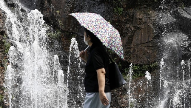 전국 대부분 지역 낮 최고 기온이 30도까지 웃돌며 더운 날씨를 보인 지난 8일 서울 서대문구 홍제천 인공폭포에서 한 시민이 양산을 들고 발걸음을 옮기고 있다.