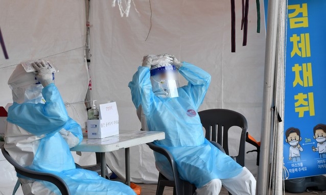 무더운 날씨가 이어진 8일 오후 부산 동래구 인공폭포 인근에 마련된 임시선별검사소에서 의료진들이 잠깐 쉬는 동안 얼음팩을 이용해 더위를 식히고 있다. 이날 부산지역 낮 최고기온은 중구 대청동 공식관측소 기준으로 26.2도를 기록했고, 지역별로는 금정구 30.6도, 동래구 및 북구 30.3도, 부산진구 29.5도, 해운대구 29도 등을 나타냈다.