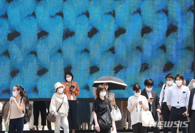 일본 수도 도쿄 시내에서 7일 코로나19 예방을 위해 마스크를 착용한 시민들이 횡단보도를 건너려고 신호를 기다리고 있다.