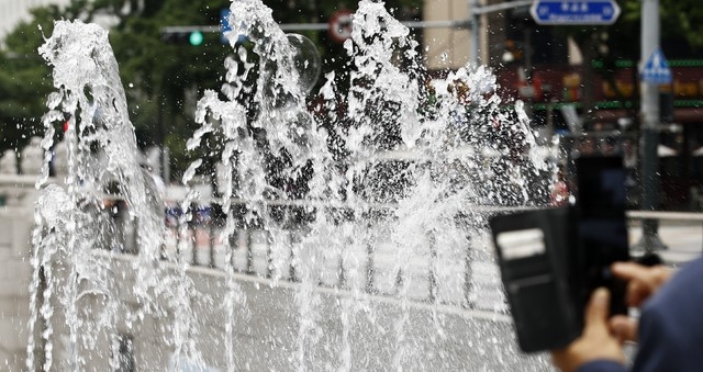 서울 낮 최고기온이 30도까지 오르는 등 더운 날씨가 이어지고 있는 지난 10일 서울 중구 청계광장에서 한 시민이 휴대폰으로 분수 사진을 찍고 있다.
