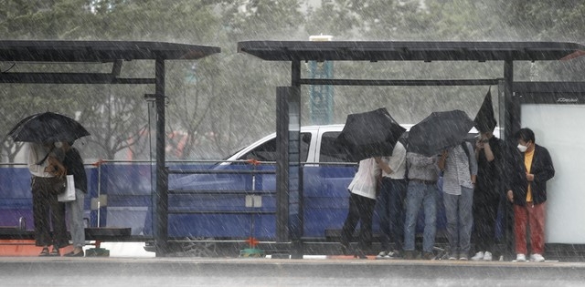 23일 서울 종로구 광화문네거리 인근 버스정류장에서 갑자기 내린 소나기에 시민들이 비를 피하고 있다.