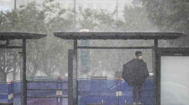 23일 서울 종로구 광화문네거리 인근 버스정류장에서 갑자기 내린 소나기에 시민이 비를 피하고 있다.