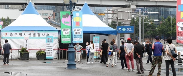 지난 26일 오전 서울 중구 서울역광장에 마련된 코로나19 임시선별검사소에서 시민들이 검사를 받기 위해 대기하고 있다.