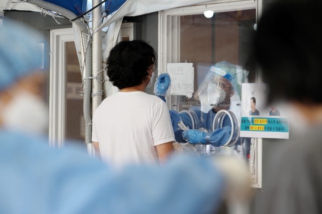 코로나19 신규 확진자가 614명으로 집계된 27일 오전 서울 중구 서울역 임시선별검사소에서 의료진이 검체 채취를 하고 있다.