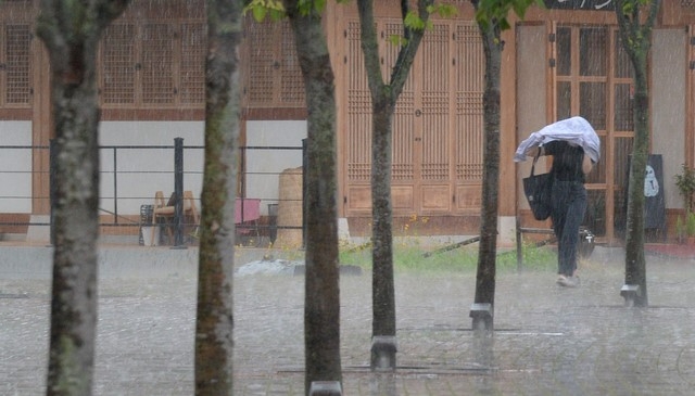 전북 전주시에 소나기와 더불어 우박이 내리기 시작한 28일 전북대학교에서 학생이 비를 피하며 교정을 지나고 있다.
