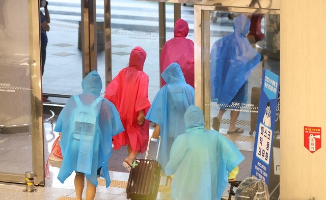 한라산 등 고지대에 많은 비가 내리는 11일 오전 제주국제공항 1층 도착장에 우비를 입은 관광객들이 이동하고 있다.