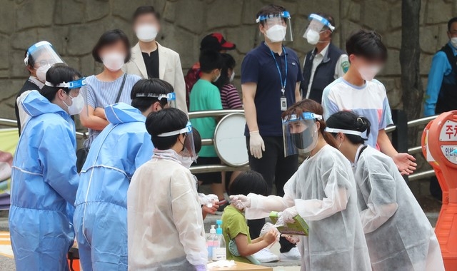 초등학생 코로나19 집단 감염이 발생한 6일 오전 인천 미추홀구 인주초등학교에 마련된 워크스루(Walk Through) 선별 진료소를 찾은 학생과 학부모, 가족들이 검사를 받기 위해 줄을 서고 있다.