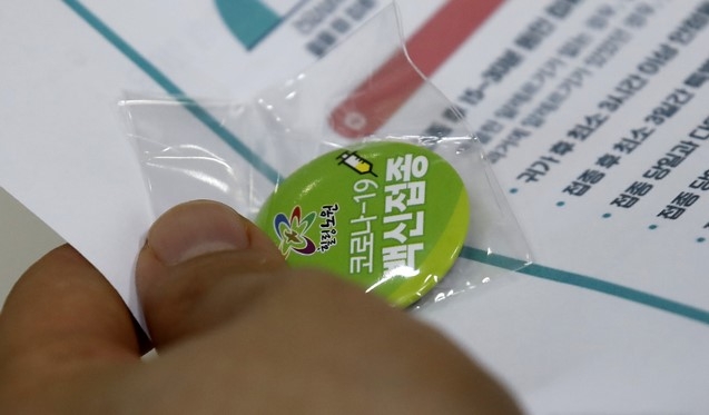 지난달 10일 서울 노원구 한 위탁의료기관에서 백신 접종을 마친 한 시민이 백신 접종 완료 뱃지를 들고있다.