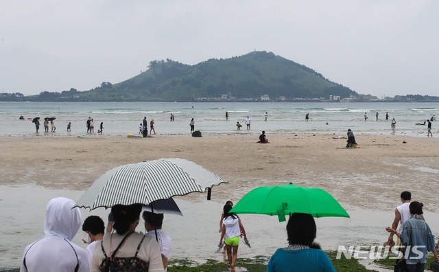 전국적으로 장맛비가 내리는 4일 오후 제주시 한림읍 금릉해수욕장에 우산을 쓴 관광객들이 바다를 응시하고 있다.