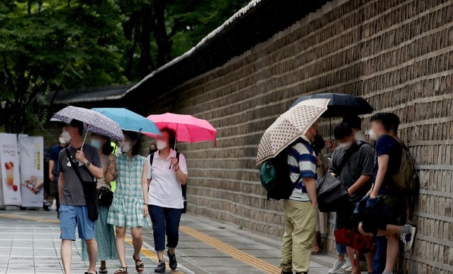 장마가 시작된 3일 오후 서울 중구 덕수궁 돌담길에서 시민들이 우산을 쓰고 있다.