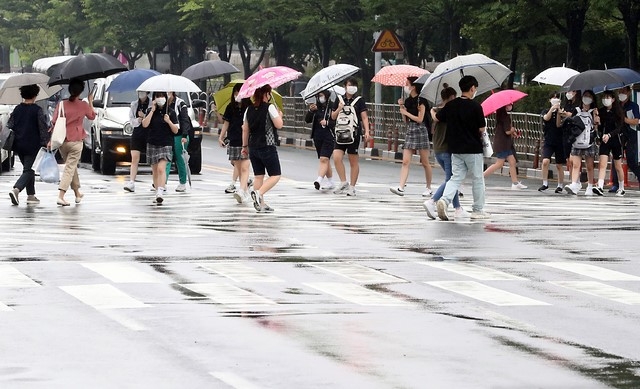 본격적인 장마가 시작된 24일 오후 인천시 남동구 터미널사거리에서 학생들이 우산을 쓰고 도로를 건너가고 있다.