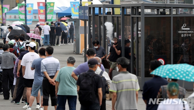 지난 10일 오전 서울 중구 서울역광장에 마련된 중구 임시선별진료소 앞에는 검사를 받기 위해 시민들이 길게 줄 서 있는 한편 흡연부스 앞에서 외국인이 흡연을 하고 있다.