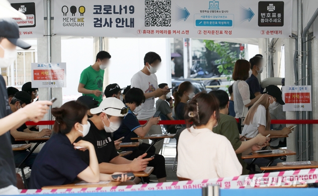 사회적 거리두기 4단계 시행 첫날인 12일 오후 서울 강남구 보건소 선별진료소에서 시민들이 검사를 받기 위해 전자문진표를 작성하고 있다.