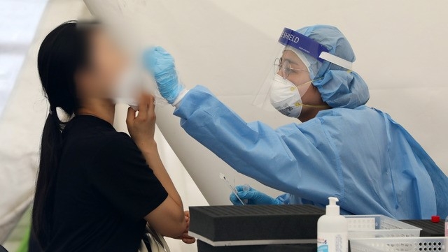 코로나19 신규 확진자가 1,615명으로 집계된 14일 오전 서울 강남구 삼성역 인근에 설치된 임시선별검사소에서 의료진이 검체 채취를 하고 있다.