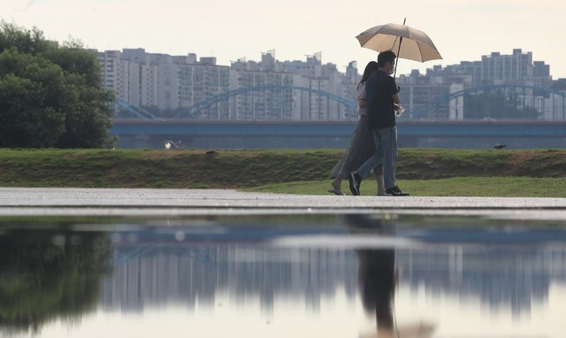폭염 속 소나기가 내린 지난 15일 서울 서초구 반포지구 한강공원에서 시민들이 우산을 쓰고 걸어가고 있다.