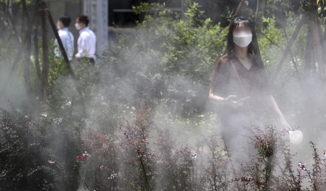 폭염이 이어지고 있는 15일 오후 서울 중구 명동에서 시민들이 쿨링포그 앞을 지나며 더위를 식히고 있다.