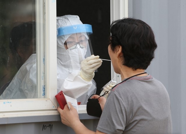 지난 19일 오후 강릉시 보건소 공무원이 강원 강릉시 유천택지 임시선별진료소에서 코로나19가 의심되는 시민의 신체에서 검체를 채취하고 있다.