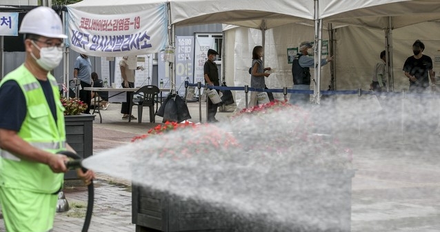 지난 19일 오전 서울 마포구 서강대역 광장에 설치된 임시선별검사소에서 마포구 관계자들이 열을 식히기 위해 선별검사소 주변에 물을 뿌리고 있다.